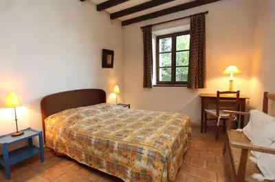 a bedroom with a bed and a window and a desk at Villa La Familliale, piscine avec vue imprenable sur Gordes in Gordes