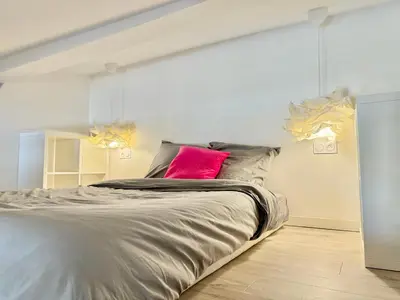 a bedroom with a large bed with a pink pillow at Appartement chic, hyper centre in Aix-en-Provence