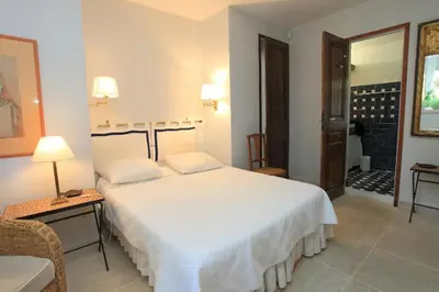 a bedroom with a large white bed and a chair at Villa La Raffinée, au coeur des garrigues du Luberon in Gordes