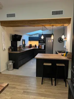 a large kitchen with a large island with two bar stools at Appartement 100 m2 au cœur de l'Isle sur la Sorgue in LʼIsle-sur-la-Sorgue