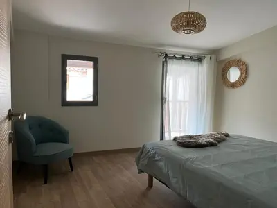 a bedroom with a bed and a chair and a window at Appartement 100 m2 au cœur de l'Isle sur la Sorgue in LʼIsle-sur-la-Sorgue