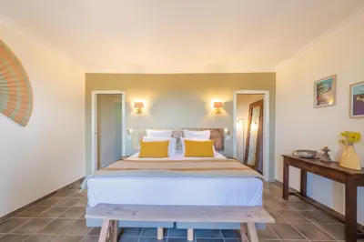 a bedroom with a large bed with yellow pillows at Le Mas Elaïa, votre havre familial avec piscine privée in Eyragues
