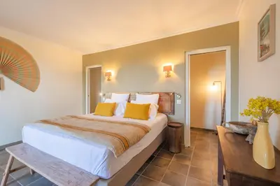 a bedroom with a large bed with yellow pillows at Le Mas Elaïa, votre havre familial avec piscine privée in Eyragues