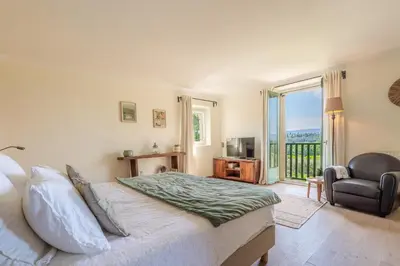 a bedroom with a large bed and a balcony at Le Mas Elaïa, votre havre familial avec piscine privée in Eyragues