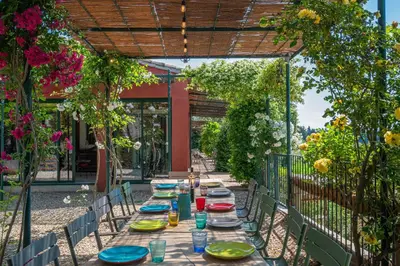 a long table with plates and glasses on a patio at Le Mas Elaïa, votre havre familial avec piscine privée in Eyragues