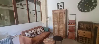 a living room with a couch and a clock on the wall at Studio cozy avec terrasse en centre ville in LʼIsle-sur-la-Sorgue