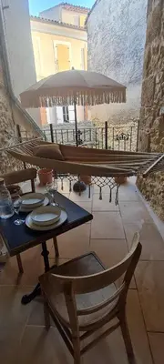 a patio with a table and chairs and an umbrella at Studio cozy avec terrasse en centre ville in LʼIsle-sur-la-Sorgue
