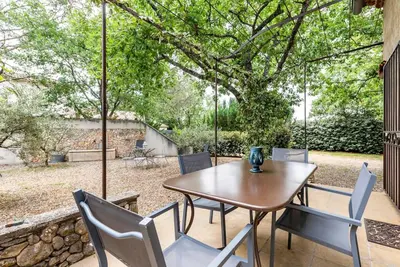 a wooden table and chairs on a patio at Le cabanon, 3 étoiles, sa piscine au pied du Luberon in Saint-Saturnin-les-Apt