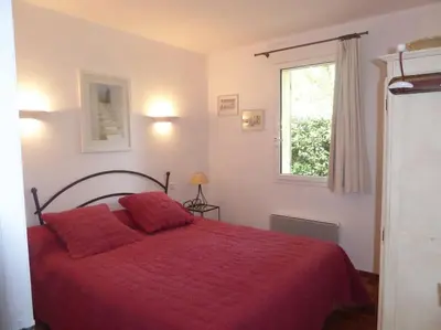a bedroom with a red bed and a window at Le cabanon, 3 étoiles, sa piscine au pied du Luberon in Saint-Saturnin-les-Apt