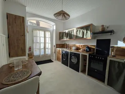 a kitchen with washing machines and a table in it at La Galatée, Balnéo et Sauna privatifs in Saint-Saturnin-lès-Avignon