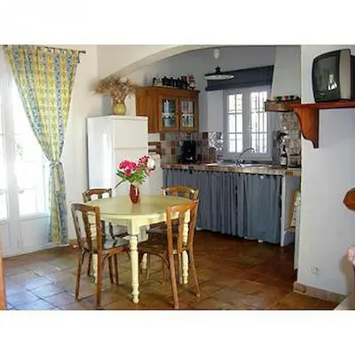 a kitchen with a table with chairs and a refrigerator at Location avec piscine Roussillon LS2-91 in Roussillon