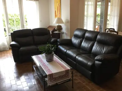 a living room with a black leather couch and a table at Maison avec piscine privative Taillades Luberon LS2-281 in Les Taillades