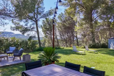 a patio with chairs and a wooden table in the grass at The Maisonnette in the pines in Ventabren
