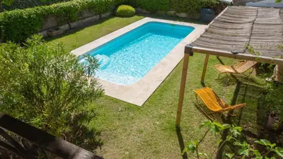 a swimming pool in a yard with a table and chairs at Au pied du Luberon in Les Taillades