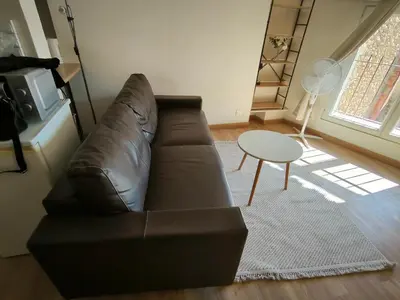 a living room with a leather couch and a table at Le Nid plein centre in Salon-de-Provence
