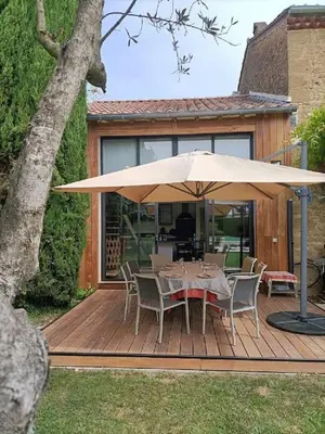 a table and chairs under an umbrella on a deck at Superbe appartement neuf au cœur de la Provence. in Entraigues-sur-la-Sorgue