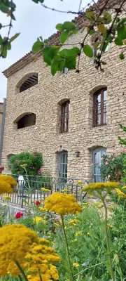 a stone building with windows and flowers in front of it at Le Cosy Luberon - Viens in Viens