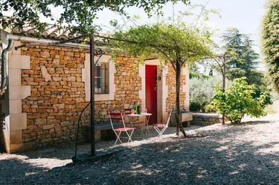 a brick house with a table and a red door at Location vacances maison piscine LIOUX LS2-92 in Lioux
