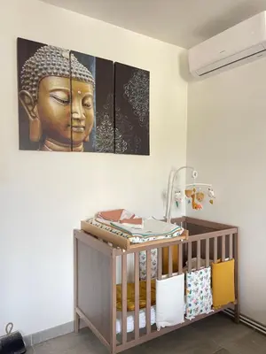 a room with a crib and a painting of a head at Entre ciel et terre in Le Thor