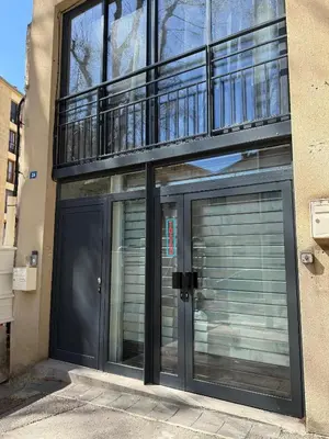 a building with two garage doors and a balcony at L'Olivier - Joli duplex au cœur du centre ville à 2 pas de la Rotonde Mirabeau et des allées Provençales in Aix-en-Provence