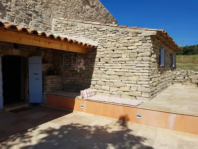 a small stone building with a porch and a patio at Maison en Luberon in Sainte-Croix-à-Lauze