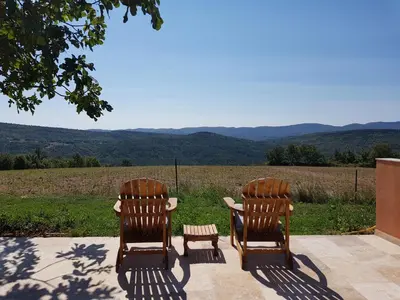two wooden chairs sitting on a patio with a view at Maison en Luberon in Sainte-Croix-à-Lauze