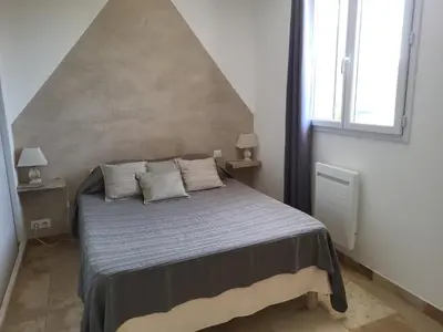 a bedroom with a bed with two night stands and two windows at L'escapade provençale in Lioux