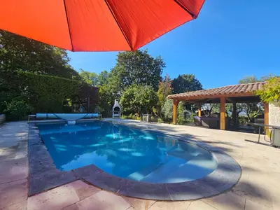 a swimming pool with an umbrella on a patio at Au Bonheur et Liberté in Meyrargues