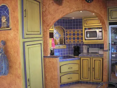 a kitchen with yellow and blue tiled walls at Au Bonheur et Liberté in Meyrargues