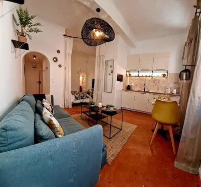 a living room with a blue couch and a kitchen at Appartement Cosy Hyper Centre Climatisé - Rue Bédarrides in Aix-en-Provence