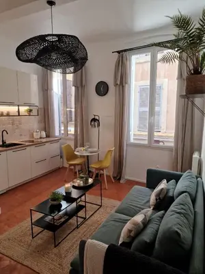 a living room with a blue couch and a kitchen at Appartement Cosy Hyper Centre Climatisé - Rue Bédarrides in Aix-en-Provence