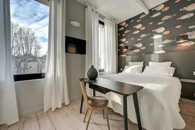 a bedroom with a bed and a table and a window at Hôtel Bellegarde by Viktor in Aix-en-Provence