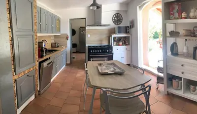 a kitchen with a table and a stove and a counter at Villa Provençale climatisée près Aix en Provence Piscine securisée alarme in Ventabren