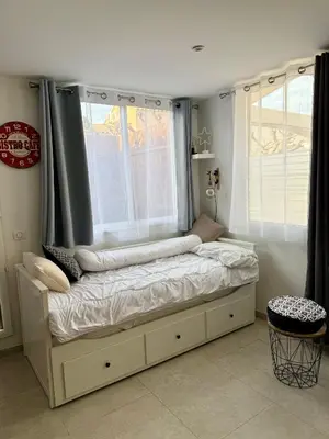a bed in a room with two windows at Le Gîte in Venelles