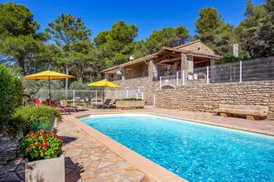 a swimming pool in front of a stone house at Villa Cheval Blanc by Villa Plus in Cheval-Blanc