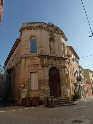 an old stone building with a statue on the front at Centre historique studio rénové avec vue in LʼIsle-sur-la-Sorgue