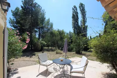 a patio with a table and chairs and an umbrella at La ferme du Loup in Cucuron