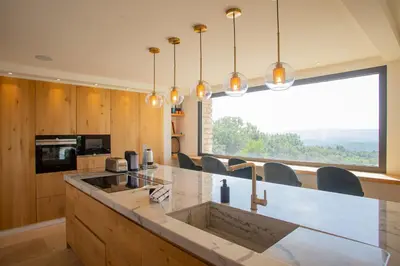 a kitchen with a counter with chairs and a large window at 8-bedroom luxury villa with pool in Gordes