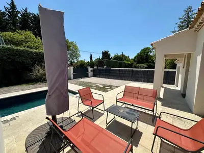 a patio with chairs and a umbrella and a table at Villa Provençale in Le Thor