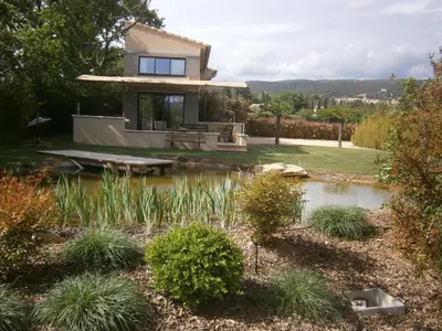 a house with a pond in front of it at L'ancien poulailler- The Old Hen House in Saint-Saturnin-les-Apt