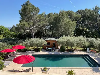 a swimming pool with two umbrellas and a house at Appel du Luberon in Mérindol