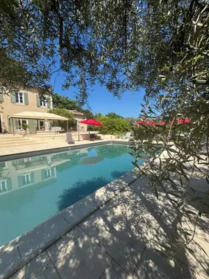 a swimming pool next to a building with a tree at Appel du Luberon in Mérindol