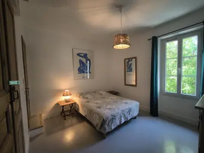 a bedroom with a bed and a window and a lamp at Le Mas des iscles Mallemort in Mallemort