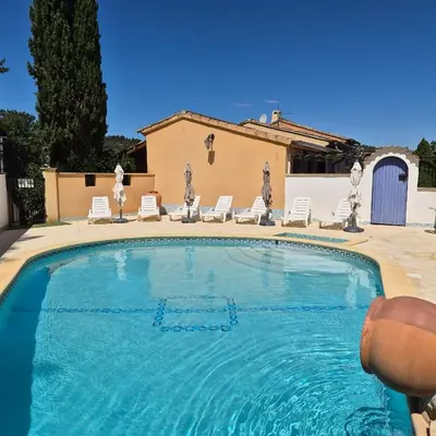 a large swimming pool with chairs and a house at Résidence Les Salettes in Mormoiron