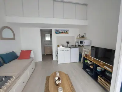 a living room with a couch and a kitchen at Studio 25m2 in LʼIsle-sur-la-Sorgue