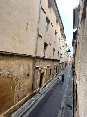 two people riding motorcycles down a street next to a building at Bel Appartement dans le centre d'Aix-en-Provence in Aix-en-Provence