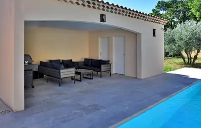 a patio with black furniture next to a swimming pool at villa in Châteauneuf-de-Gadagne