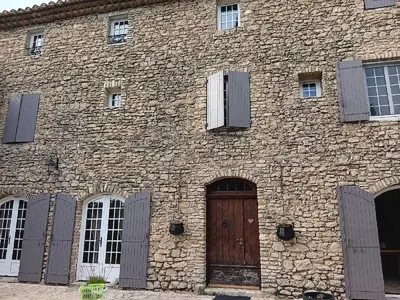 a brick building with a wooden door and windows at LE Mas Pacha in LʼIsle-sur-la-Sorgue