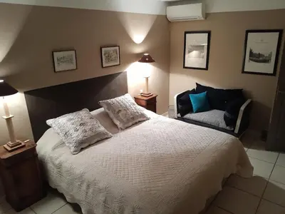 a bedroom with a large white bed and a chair at La Bartavelle in Eyragues