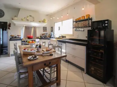 a kitchen with a wooden table and a black refrigerator at La Bartavelle in Eyragues